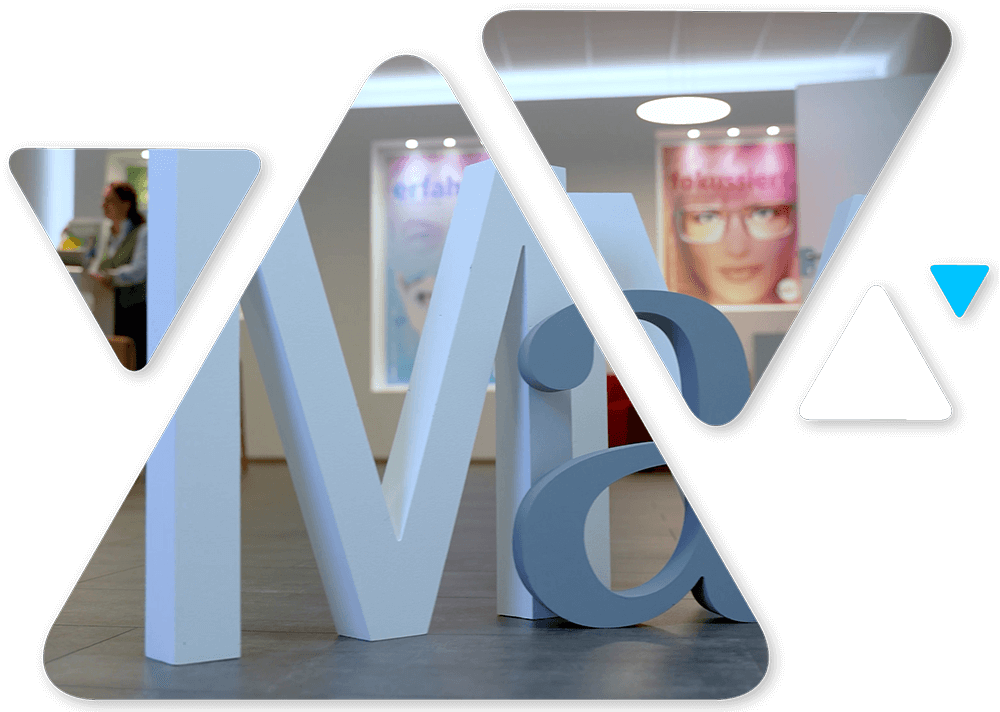 Brand logo featuring oversized white M and V shapes within a rounded frame and a blue triangle accent on the right side, set over a photo backdrop.