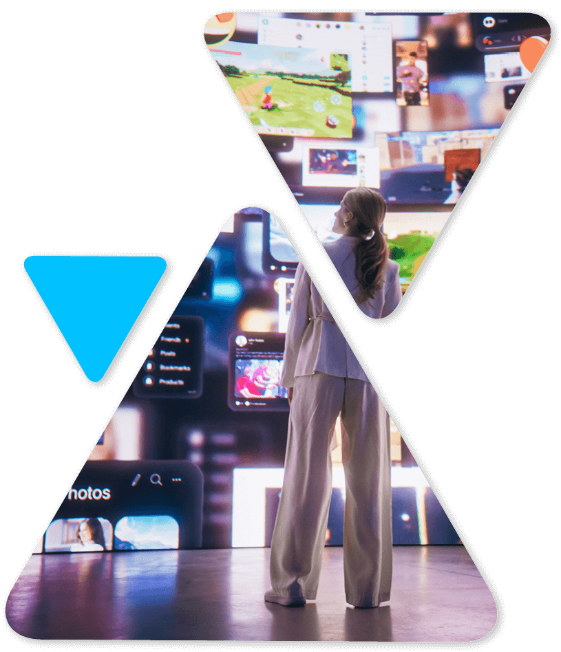 Woman in light clothing stands in front of a wall of glowing screens displaying videos and apps in a high-tech exhibit.